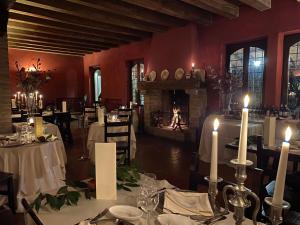 una sala da pranzo con tavoli, candele e un camino di Torre del Barbagianni - Castello di Gropparello a Gropparello
