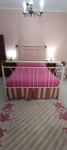 een roze bed met kussens in een slaapkamer bij La casa del ponte romano in Pogi