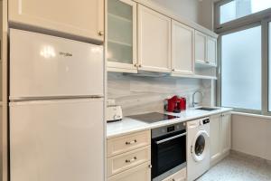  La cuisine est équipée de placards blancs et d'un réfrigérateur. dans l'établissement Athenian Vintage Apartments, à Athènes