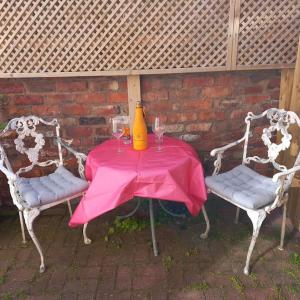 una mesa rosa con dos sillas y un jarrón encima en Beautiful self-contained annex/Cottage, en Hoylake