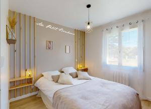 Un dormitorio con una gran cama blanca y una ventana en Au petit bonheur, en Le Bugue
