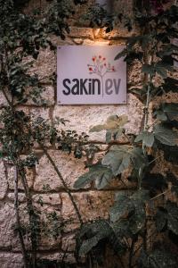 a sign on the side of a brick wall with plants at Sakin Ev in Alacati