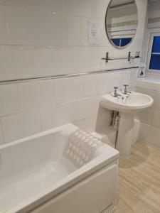 a white bathroom with a sink and a mirror at St Quintin Arms in Harpham