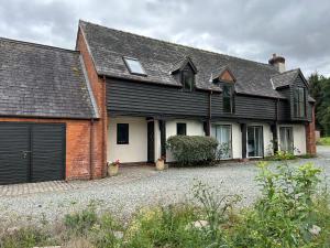 uma casa com um telhado preto e uma garagem em Owlbury Hall Barn em Montgomery