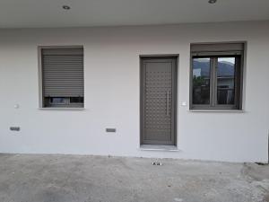 biały budynek z dwoma oknami i drzwiami w obiekcie Antigoni Apartment w mieście Suda
