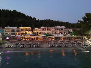 a resort with a bunch of tables and chairs next to the water at Olympion Sunset Halkidiki in Fourka