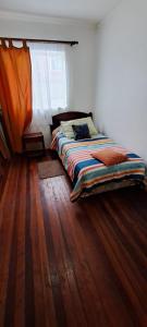 Bett in einem Zimmer mit Holzboden in der Unterkunft Casa al lado del Casino in Coihaique