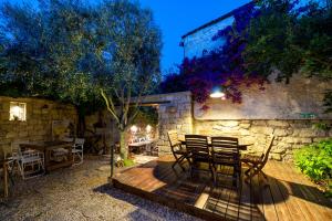 a patio with a table and chairs and a stone wall at Sakin Ev in Alacati