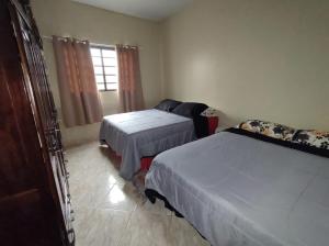 a bedroom with two beds and a couch and a window at Casa Simples e Agradável da Lu in Alto Paraíso de Goiás