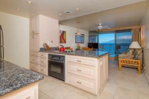 a kitchen with white cabinets and a view of the ocean at Kahana Reef #402 in Kahana