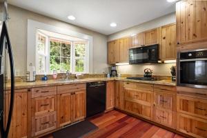 uma cozinha com armários de madeira e electrodomésticos pretos em Stylish Cabin em Orick