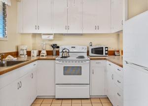 a white kitchen with a stove and a microwave at Exquisite Honokowai Palms Unit #A-7 in Kahana