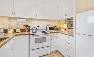 a kitchen with white cabinets and a white stove top oven at Exquisite Honokowai Palms Unit #A-7 in Kahana