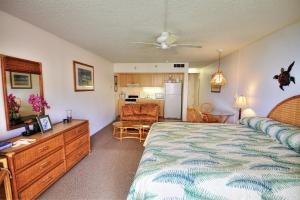 a bedroom with a large bed and a kitchen at Royal Kahana #319 in Kahana