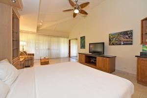 a bedroom with a white bed and a flat screen tv at Maui Kaanapali Villas #D271 in Lahaina