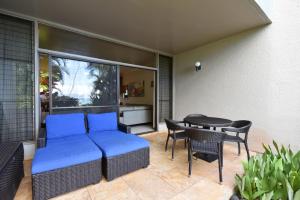 un patio con un sofá azul y una mesa en Hale Mahina #B102 en Kahana