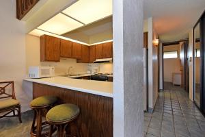 a kitchen with wooden cabinets and bar stools at Papakea Condo Unit D402 in Kahana