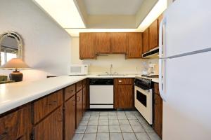 a kitchen with wooden cabinets and a white refrigerator at Papakea Condo Unit D402 in Kahana