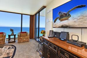 a living room with a large screen tv and a desk at Mahana Resort #1104 in Kahana