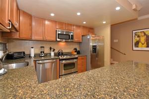 a kitchen with stainless steel appliances and wooden cabinets at Hale Mahina B101 in Kahana