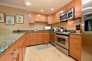 a kitchen with wooden cabinets and stainless steel appliances at Hale Mahina B101 in Kahana