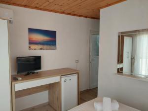 Habitación con escritorio y TV en la pared. en Qeparo Antonio Rooms en Qeparo