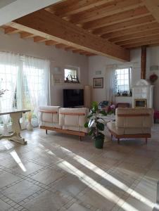 una gran sala de estar con muebles blancos y techo de madera. en Il Giardino nella Valle, en Belvedere Ostrense