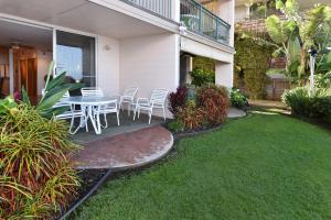 a patio with a table and chairs in a yard at Makani Sands #102 in Kahana