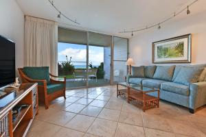 a living room with a couch and a tv at Makani Sands #102 in Kahana