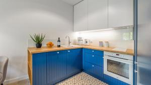 a kitchen with blue cabinets and a sink at Lazurowe Wybrzeże z widokiem na morze - Perłowa Przystań - Holiday City in Sianozety