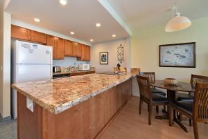une cuisine et une salle à manger avec une table et un réfrigérateur dans l'établissement Kahana Reef #414, à Kahana