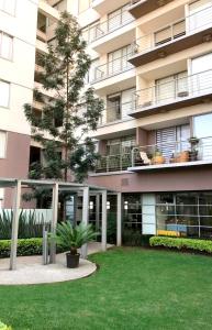 an apartment building with a green lawn in front of it at Casa Vive Grand by Kukun in Mexico City