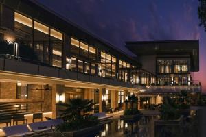 JW Marriott Hotel Bengaluru Prestige Golfshire Resort & Spa في بانغالور: مبنى أمامه مسبح في الليل