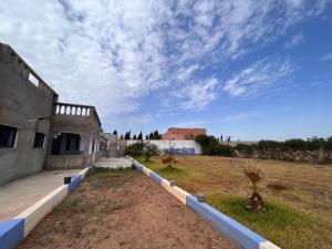 a building in a field with a cloudy sky at Abou Cristal House 