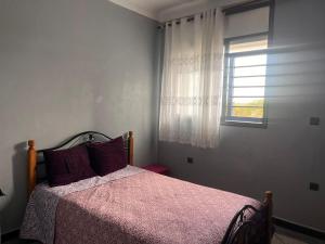 1 dormitorio con 1 cama con manta rosa y ventana en Abou Cristal House, 