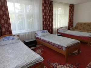 een kleine kamer met 2 bedden en een bank bij Meerim Guest House in Bokonbayevo