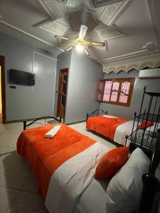 a bedroom with two beds and a ceiling fan at Riad Perlamazigh in Zagora
