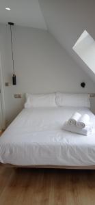 Una cama blanca con dos toallas plegables. en Príncipe Boutique apartments, en Vigo