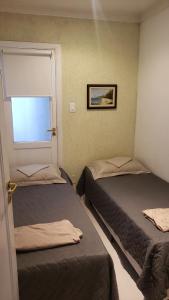 two beds in a small room with a window at Frente Ao Mar in Santos