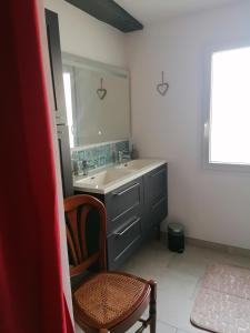 ein Badezimmer mit einem Waschbecken, einem Spiegel und einem Stuhl in der Unterkunft La Maison des Amis in Les Essarts