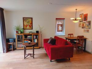 a living room with a red couch and a table at KnusinTwente in Geesteren