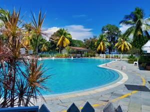 a swimming pool with palm trees and a blue sky at 1-5Pax Bayu Beach SEAFRONT, FREE BBQ, STEAMBOAT, POOL, WATER SPORT in Port Dickson