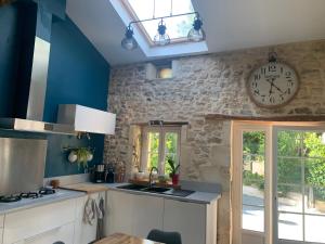eine Küche mit einer Uhr an der Wand und einem Waschbecken in der Unterkunft Les 5 timbres in Montpellier-de-Médillan