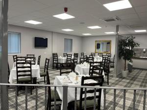 uma sala de jantar com mesas e cadeiras e uma televisão em Harleys Inn em Chesterfield