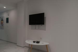 een flatscreen-tv op een witte muur met een tafel bij Athens Jacuzzi apartment in Athene
