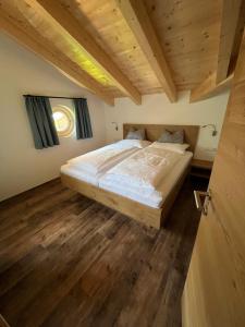 Cama grande en habitación con suelo de madera en Gstinighof, en Ainet