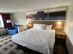 a hotel room with a bed and a blue chair at Days-Inn by Wyndham Liverpool-Syracuse in Liverpool