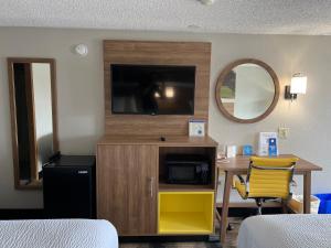 a hotel room with a tv and a desk with a bed at Days-Inn by Wyndham Liverpool-Syracuse in Liverpool