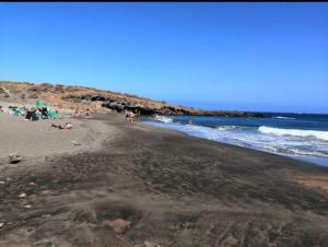 un groupe de personnes sur une plage avec l'océan dans l'établissement Casa barbacoa, patio en la playa, à Santa Cruz de Tenerife