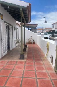 une terrasse couverte d'une maison avec un trottoir carrelé rouge dans l'établissement Casa barbacoa, patio en la playa, à Santa Cruz de Tenerife